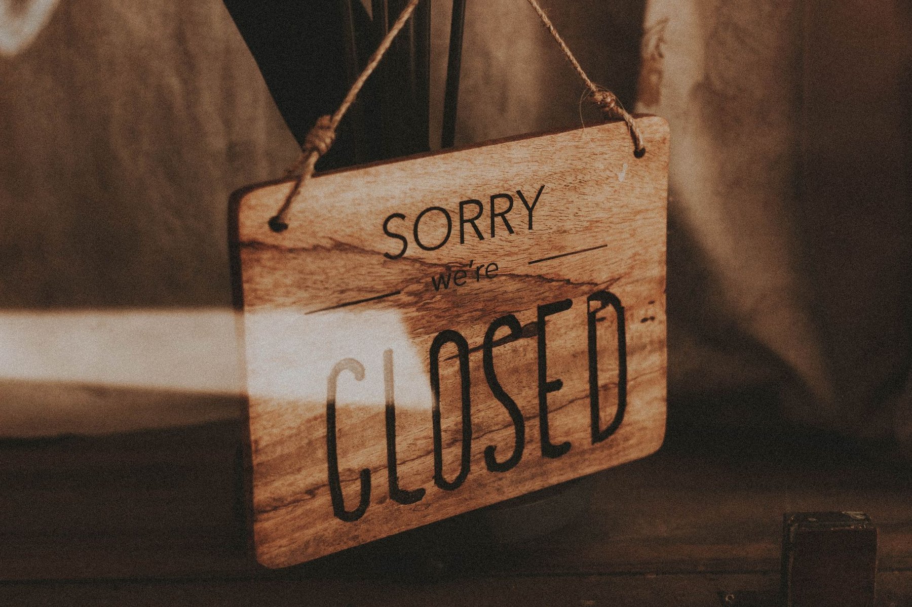Wooden 'Sorry we're closed' sign hanging on a shop door, representing closing a business and cancelling an ABN