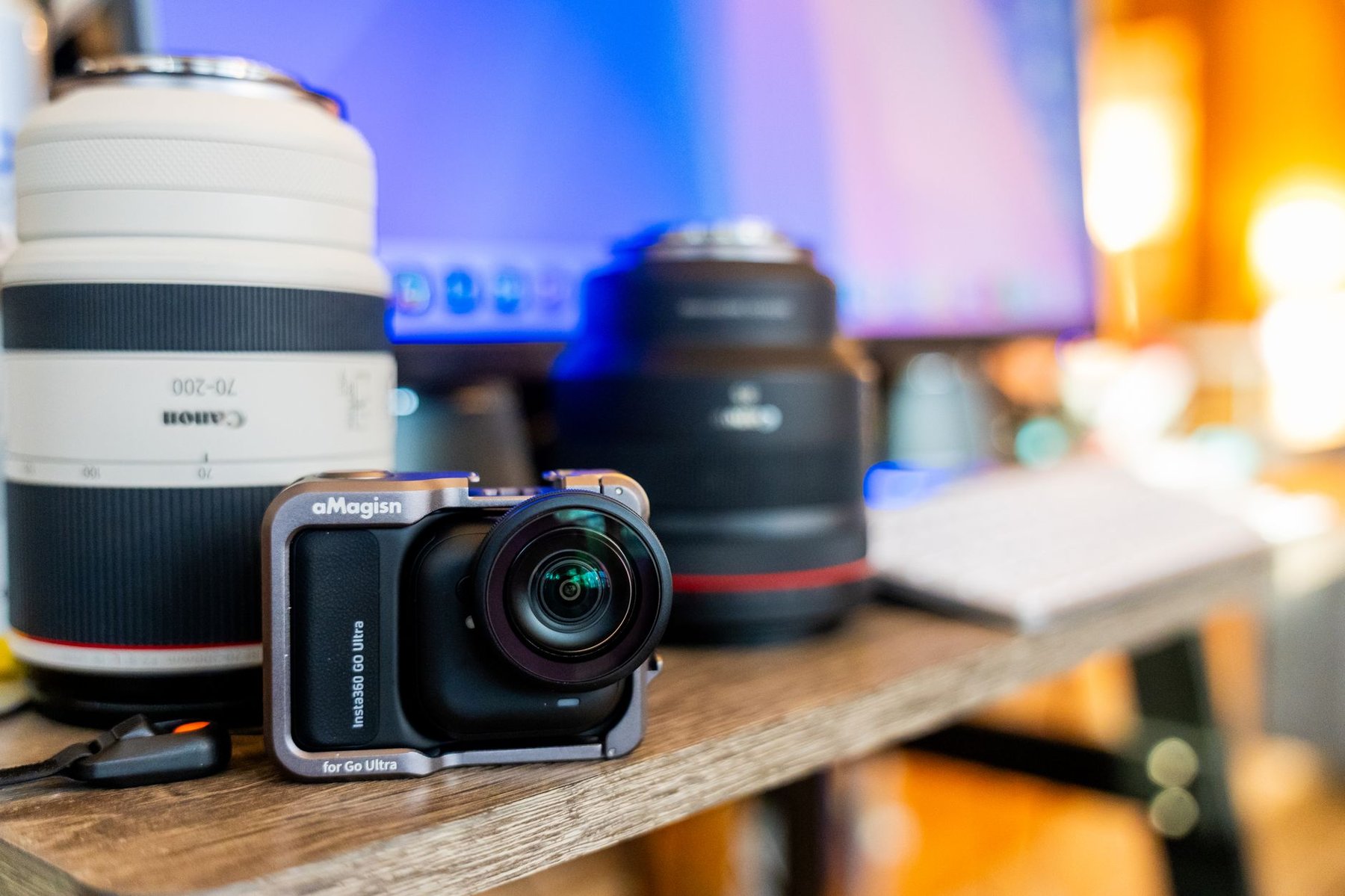 Compact camera and professional telephoto lenses on a wooden desk in a creative studio, the kind of equipment creatives save up to buy