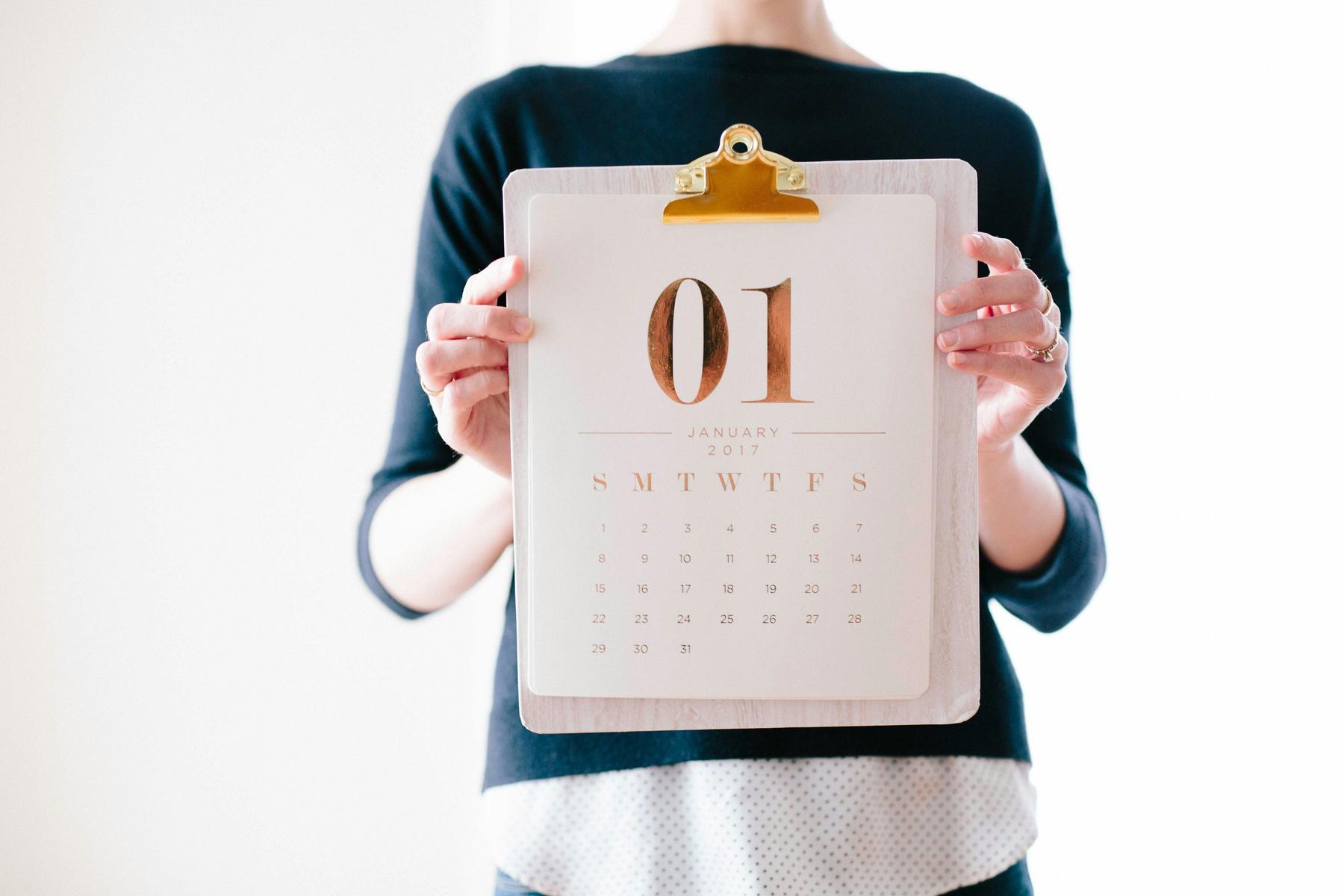 Person holding a clipboard with a calendar page displaying "January 01, 2017.