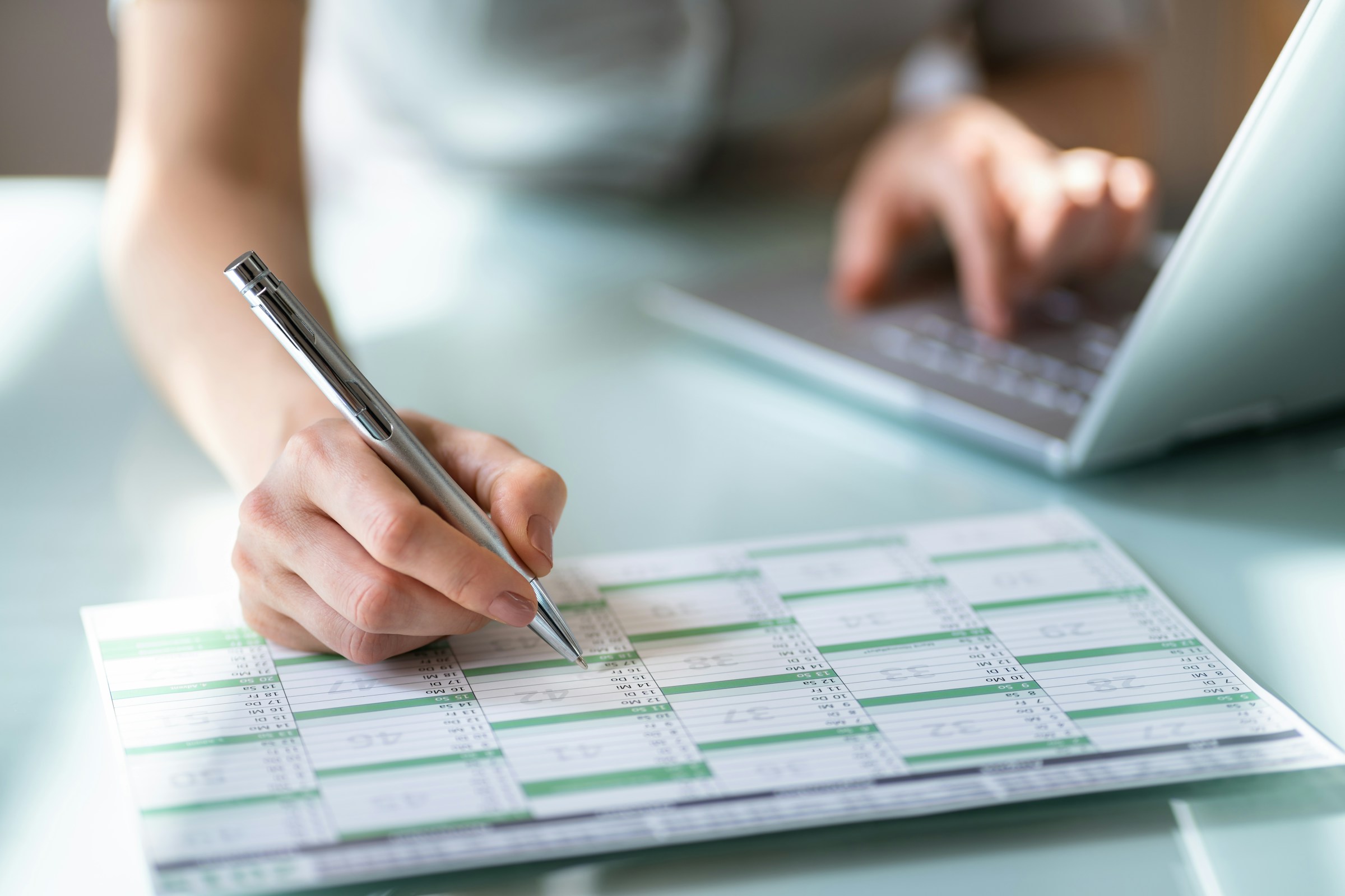 With a silver pen poised over the calendar, the person diligently notes important dates, including the crucial "When Are Taxes Due" deadline, while a laptop hums quietly in the background.